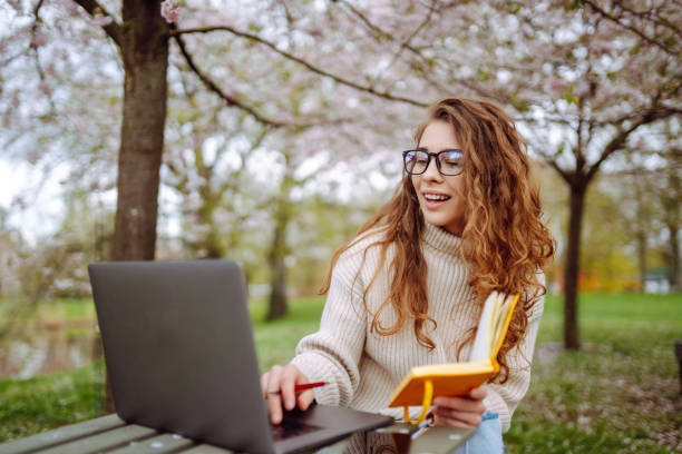 istock Young female student sitting in park with a laptop. 2045833400