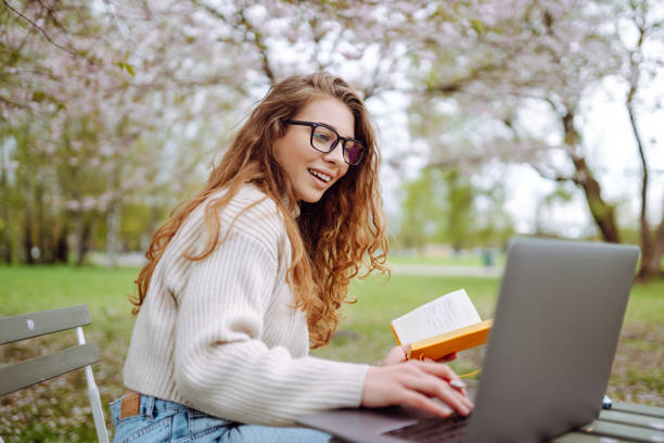istock Young female student sitting in park with a laptop. 2045833911
