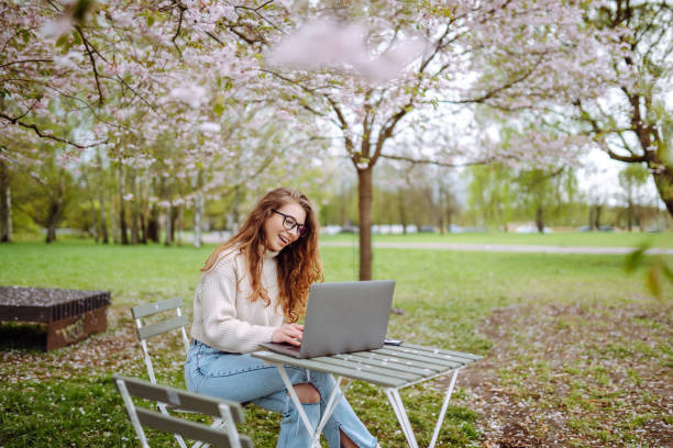 istock Young female student sitting in park with a laptop. 2045834435