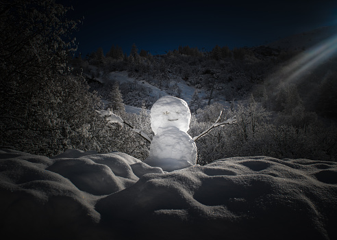 Snowman lit by a ray of sunlight at the foot of the slopes of a ski resort