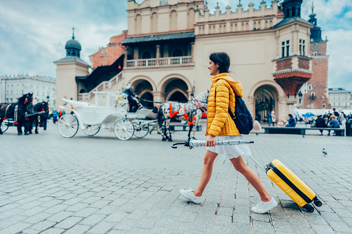 Woman with suitcase and umbrella relocate to live in Krakow