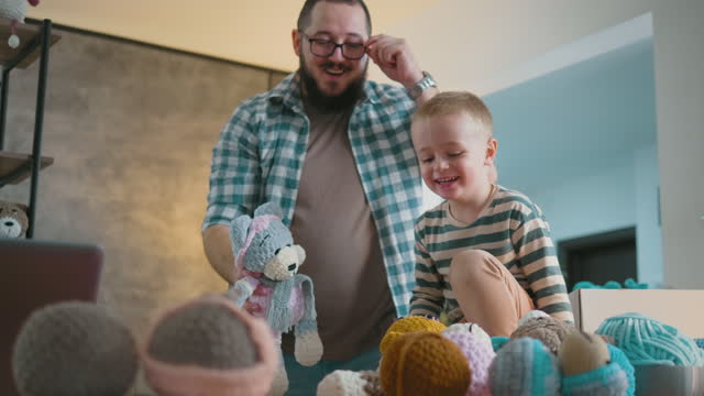 Father and little son play and have fun with their crocheted toy products that they make and sell small family business