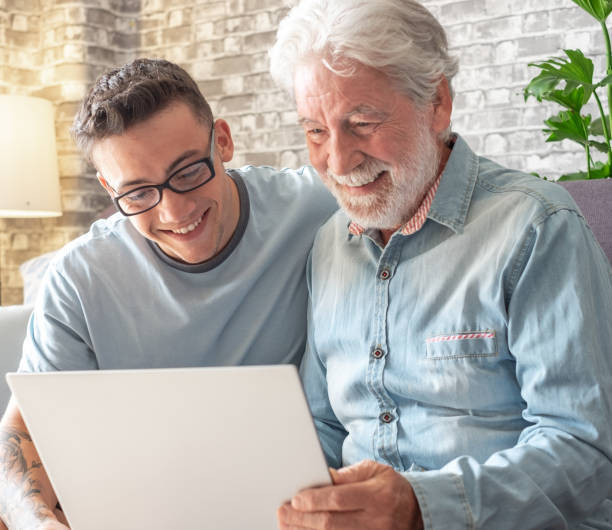 istock Smiling experienced young boy with laptop teaching and showing new computer technology to his old grandfather for surfing internet, shopping online, managing bank. Old man learns to use the computer 2045915514