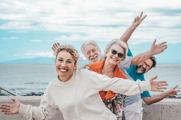 istock Happy playful multigenerational family group outdoors at seaside expressing joy by gesturing with hands towards camera 2045921754