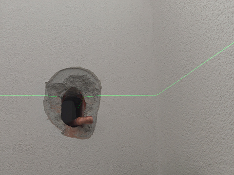 Laser level used to precise position pipes on house wall