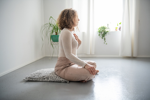 Woman practicing Feldenkrais method through the movement  and doing yoga at home. Zen vibe, breathing relaxing exercises.