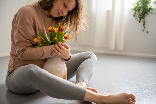 Woman with tulips sitting on the floor.