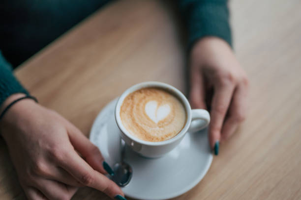 istock Female hands holding coffee cup on wooden table. 2045950247