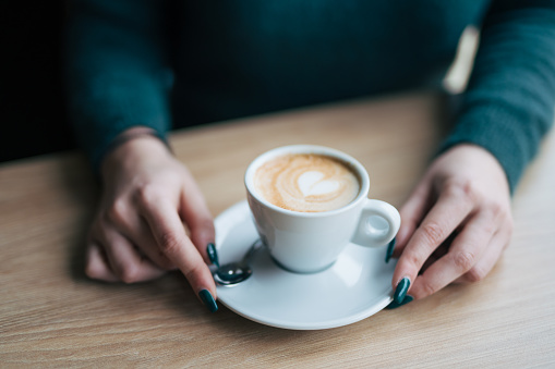 Female hands holding coffee cup  on wooden table. Close up picture.