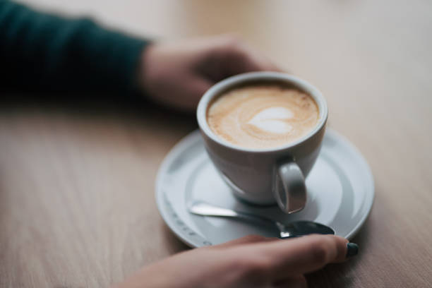 istock Female hands holding coffee cup on wooden table. 2045953765