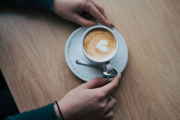 istock Female hands holding coffee cup on wooden table. 2045953766