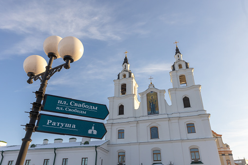 Minsk, Belarus - January 7, 2024: Street signs and the Minsk Cathedral of the Holy Spirit on the background. Text means Liberty town square and Town hall in Belarusian and Russian languages