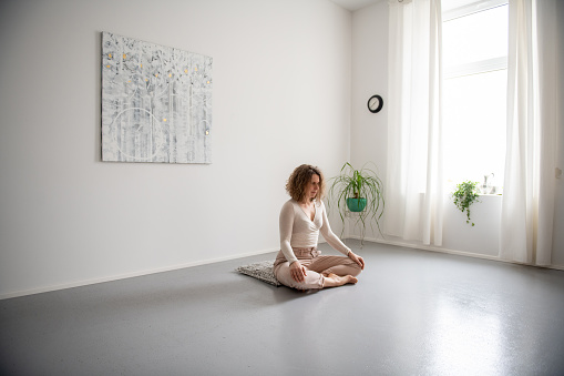 Woman practicing Feldenkrais method through the movement  and doing yoga at home. Zen vibe, breathing relaxing exercises.