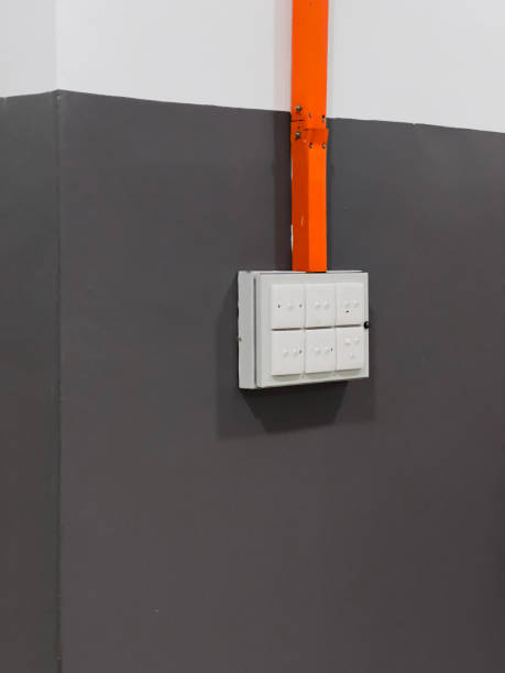 istock A minimalist and modern light switch panel on a dark grey wall with an orange conduit pipe adding a splash of color. 2045967664