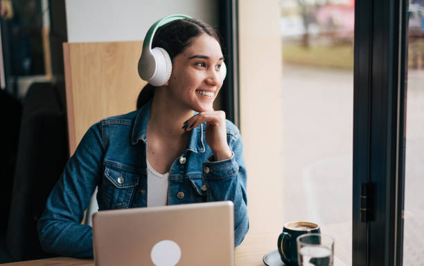 istock Smiling young woman sitting with laptop in cafe 2045973067