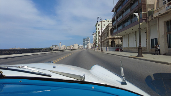 POV through old vehicle to city street in Havana City