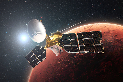 Technological satellite flies in orbit of the red planet Mars. Exploring the planet Mars. Surface of Mars with craters in stellar space with the sun. Mars Reconnaissance Orbiter