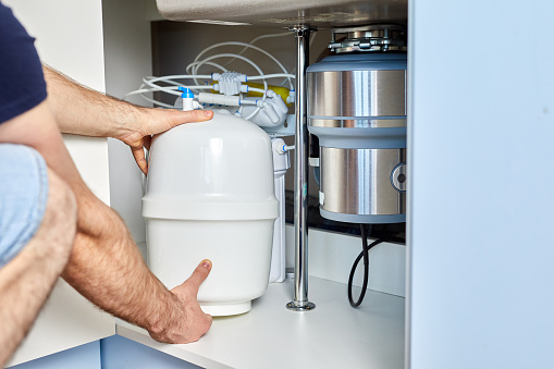 Plumber installs reverse osmosis equipment under the sink. The master installs a water filter in the kitchen. Installation of the cleaning system.