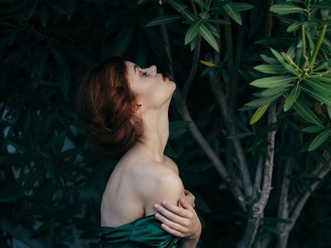 woman with bare shoulders looking up leaves exotic. High quality photo