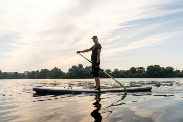 istock Young man leisurely glides on paddleboard across urban lake 2045997252