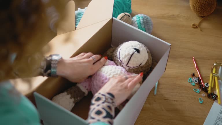 Family business concept, close up packing crocheted stuffed toys in a box ready for delivery