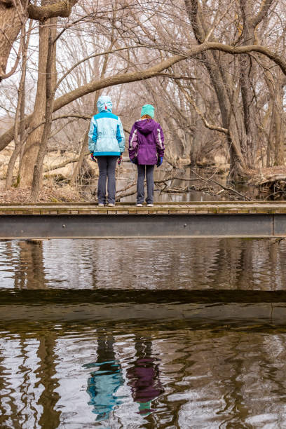istock Two Girls Standing on Bridge in Springtime Woods 2046010195