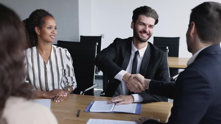 Positive young business partner men in formal suits shaking hands