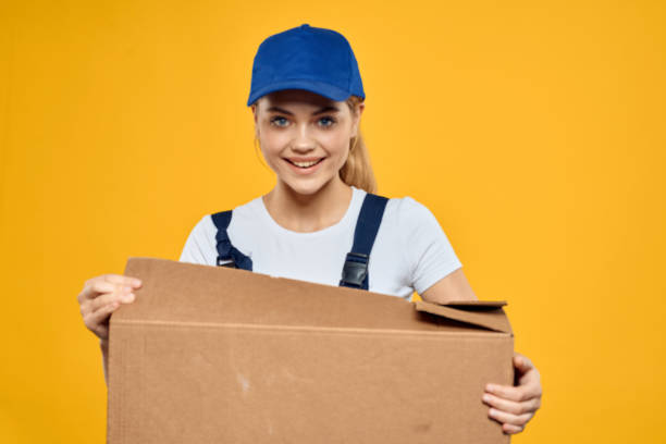 istock Working woman in uniform box in hands delivery courier service rendering yellow background 2046018593