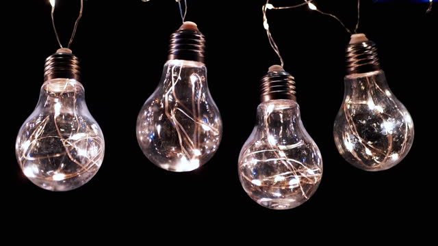 Lots Hanging Flickering Glowing Vintage Edison Light Bulbs on a Black Background
