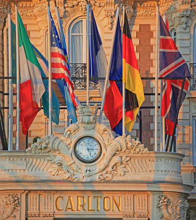 Cannes, France - January 20, 2012: International Flags and IWC Clock at Luxury Carlton Five Star Hotel Sunny Winter Day French Riviera.