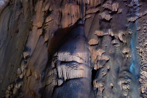 Stalactites and stalagmites illuminated with colored lighting, natural cave.