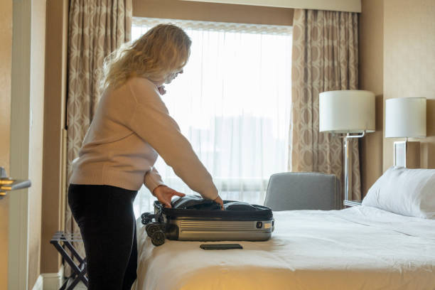 istock Mature woman opens suitcase on bed 2046090421