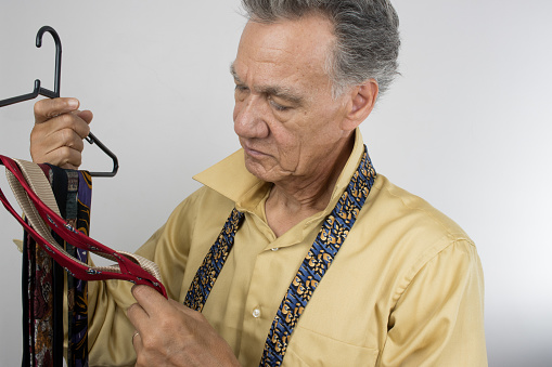 Mature Senior Man trying to select a necktie to wear