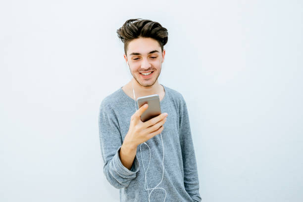 istock Portrait of young boy using mobile phone in front of white wall 2046112613