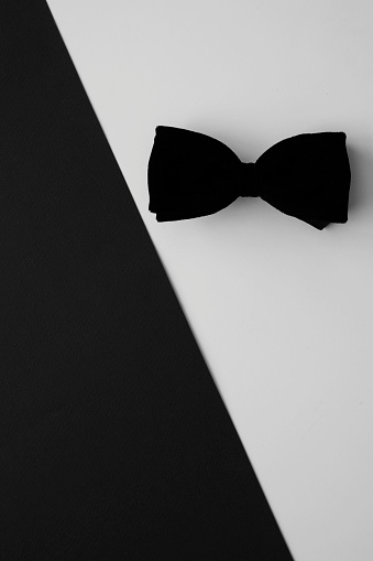 Black bow tie on white and black background.