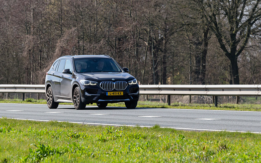 Netherlands, Overijssel, Twente, Wierden, March 19th 2023, side/front view close-up of a Dutch brown 2021 BMW 2nd generation W X1 'Sdrive20i'  station wagon driving on the N36 at Wierden, the X1 has been made by German manufacturer \