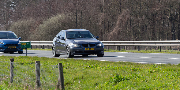 Netherlands, Overijssel, Twente, Wierden, March 19th 2023, side/front view close-up of a Dutch gray 2006 BMW 5th generation 3-series 318 diesel sedan driving on the N36 at Wierden, the 3-series has been made by German manufacturer 