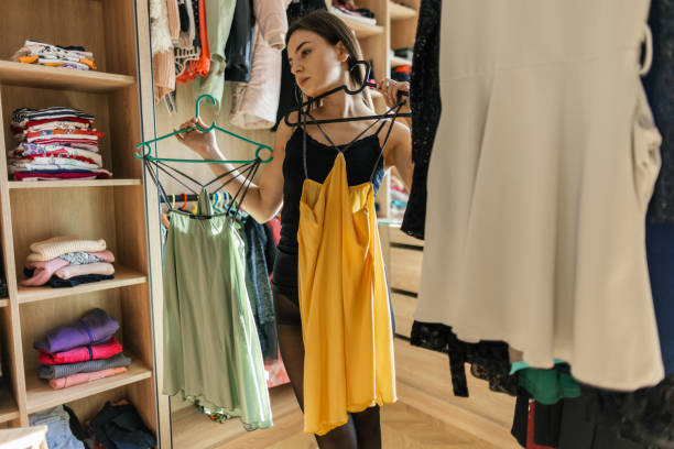 mujer joven probando vestidos en casa - placard women holding standing fotografías e imágenes de stock