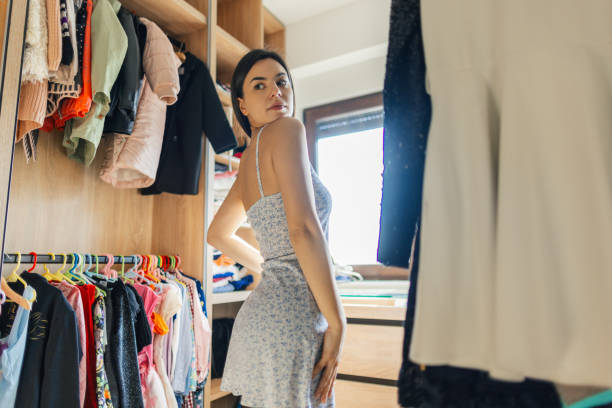 young woman trying out dresses at home - placard women holding standing fotografías e imágenes de stock