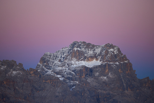 Dolomites mountains before sunrise, the sky is purple and blue the first snow of the year is on the top of the mountains