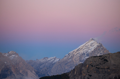 Dolomites mountains before sunrise, the sky is purple and blue the first snow of the year is on the top of the mountains