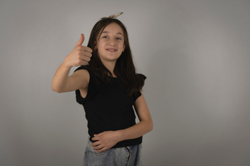 White-skinned Latina girl with short hair is inside a photo studio where she models a line of children's clothing while enjoying the moment and looking at the camera.