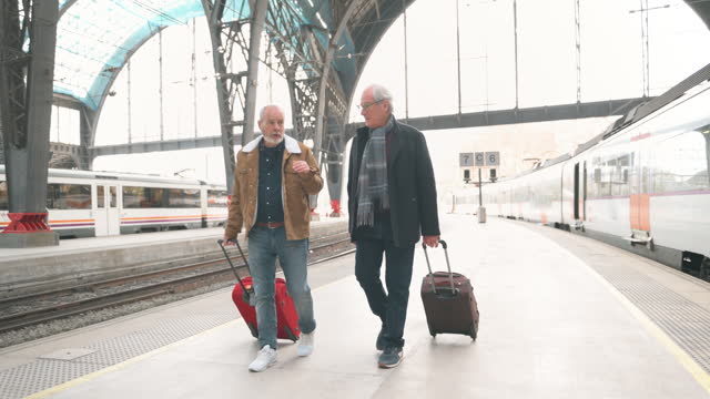 Senior male friends arrive at train station