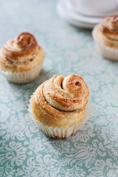 Sweet croissant muffins - cruffins- puff pastry cakes in paper cups; Easter dough mini rolls with sugar sprinkles and cinnamon filling