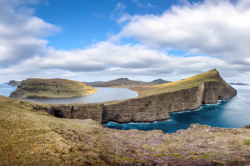 Trælanípa and Lake Leitisvatn, Vágar, Faroe Islands: Trælanípa is a rock wall, which juts 142 metres upwards out of the sea.\n\nLake Leitisvatn is the largest lake in the Faroe Islands. The lake has also been named “the lake over the ocean” as the view from Trælanípan from a particular angle functions as an optical illusion, appearing to look as though the lake is hovering directly above the ocean.