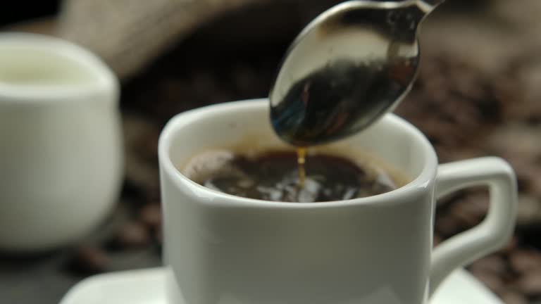 Close-up of a spoon stirring coffee in a white porcelain cup