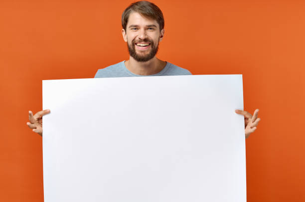 istock happy guy with mockup in hand poster orange background Copy Space 2046192480