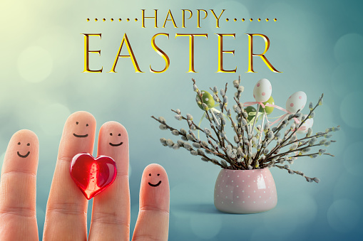 Pussy willow twigs with catkins and Easter eggs in a vase and happy finger family with a red heart. Happy Easter lettering. Defocused lights bokeh background.