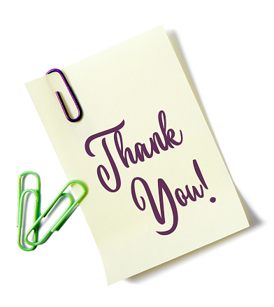 'Thank you' written on a paper note with paper clips. Isolated on a white background.