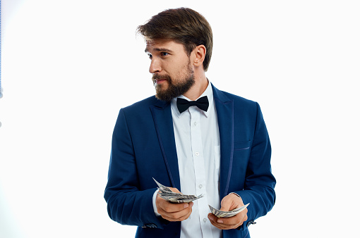 a rich man in a classic suit on a light background with a bundle of money in his hands. High quality photo